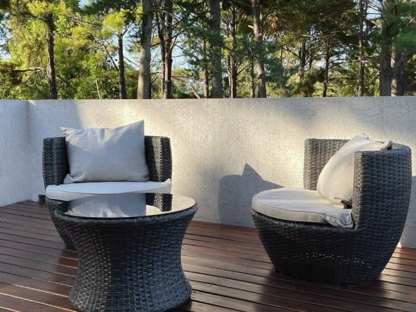 Juego Capri en espacios naturales Juego de exterior Capri con estructura de ratán sintético oscuro y almohadones beige, ideal para terrazas o jardines rodeados de naturaleza.